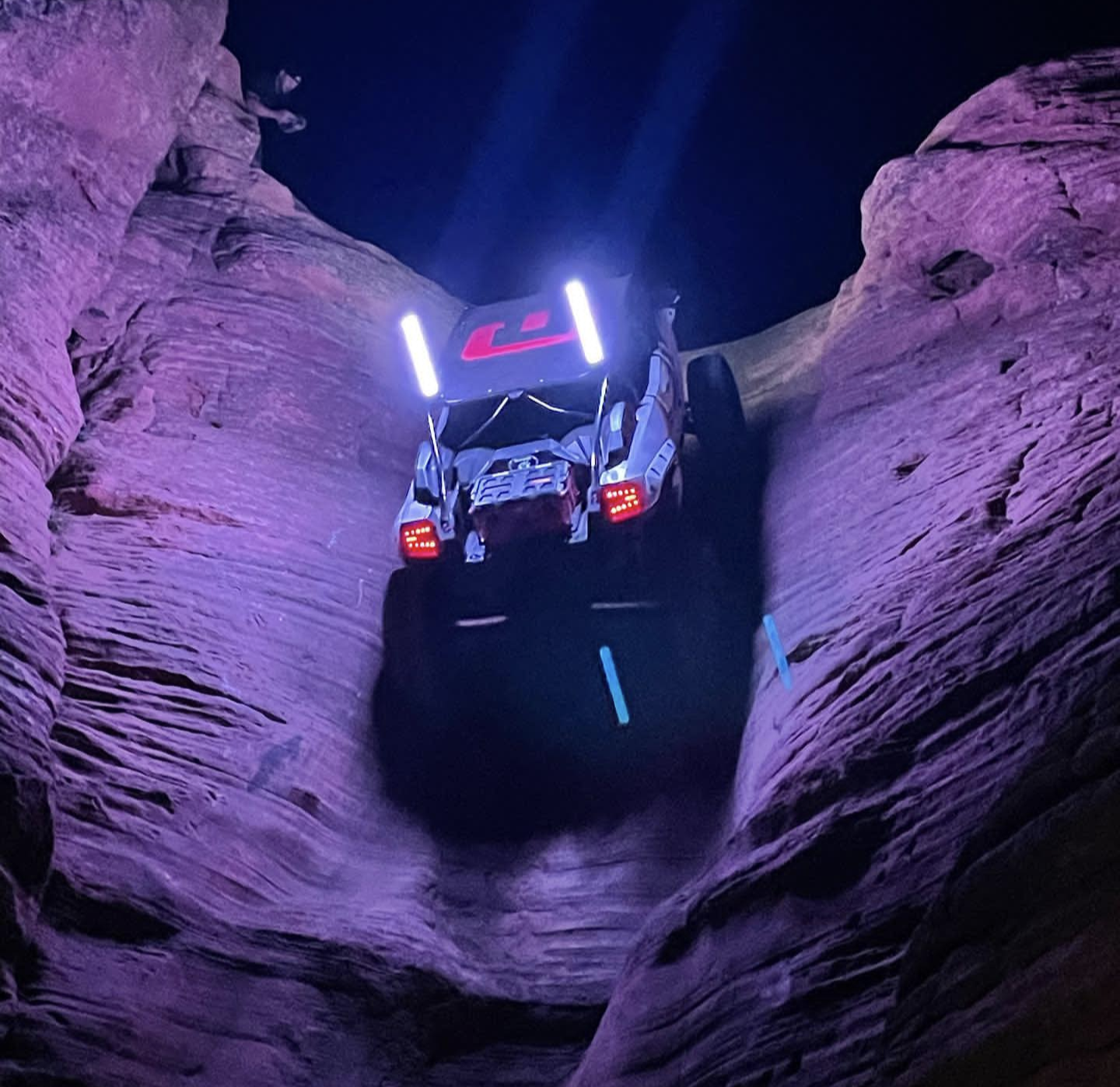 NoCo Whips LED whips illuminating a UTV climbing between canyon walls at night